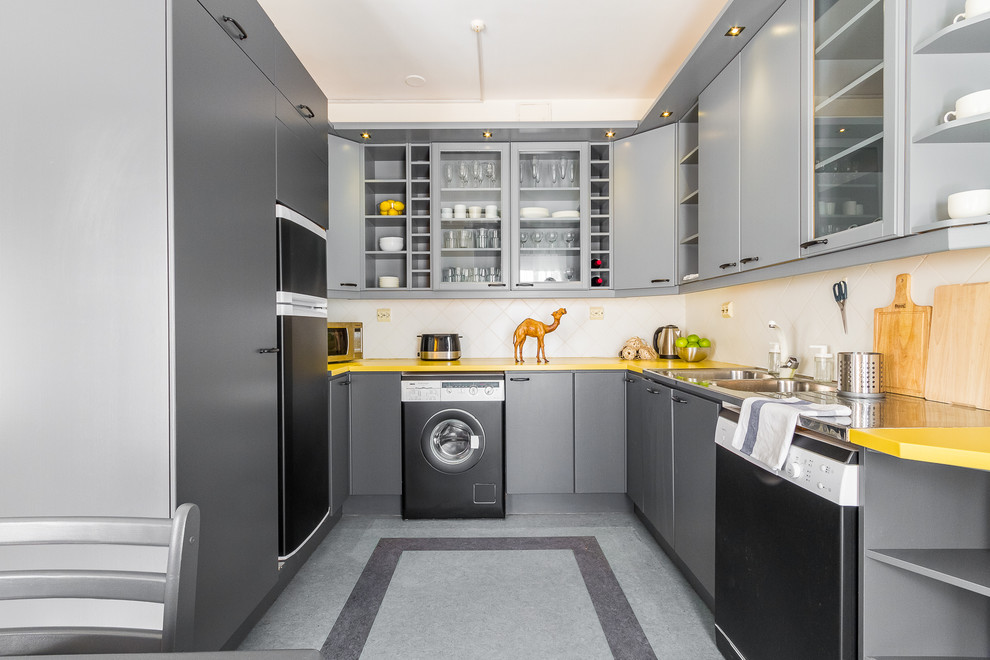 Design ideas for a scandinavian u-shaped kitchen in Moscow with a drop-in sink, flat-panel cabinets, grey cabinets, white splashback, black appliances, grey floor and yellow benchtop.