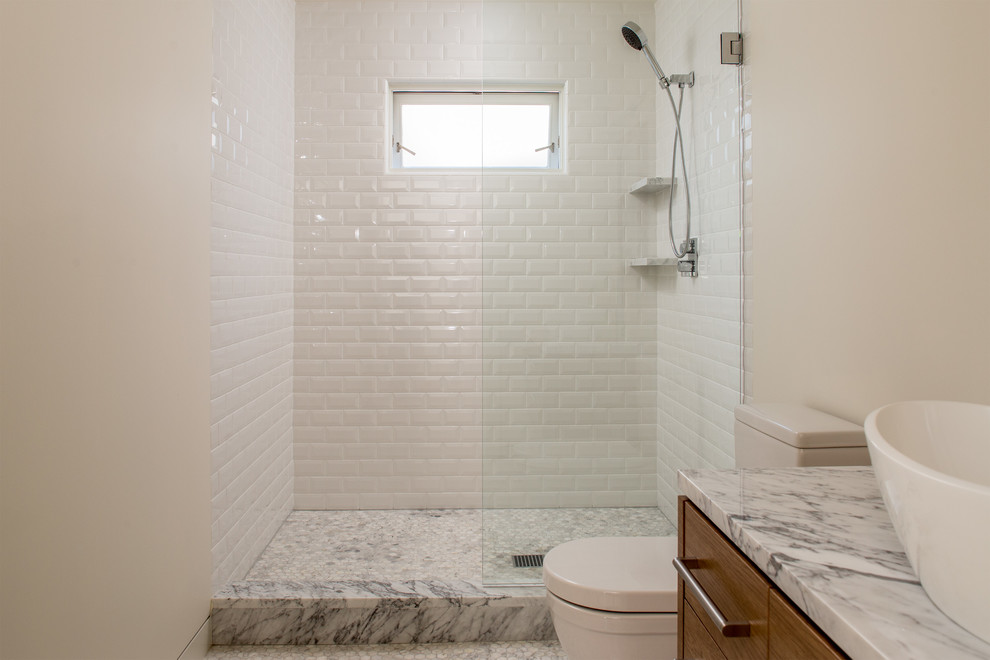 This is an example of a modern bathroom in San Francisco with a vessel sink, flat-panel cabinets, medium wood cabinets, marble benchtops, a freestanding tub, an alcove shower, white tile, porcelain tile, white walls and marble floors.