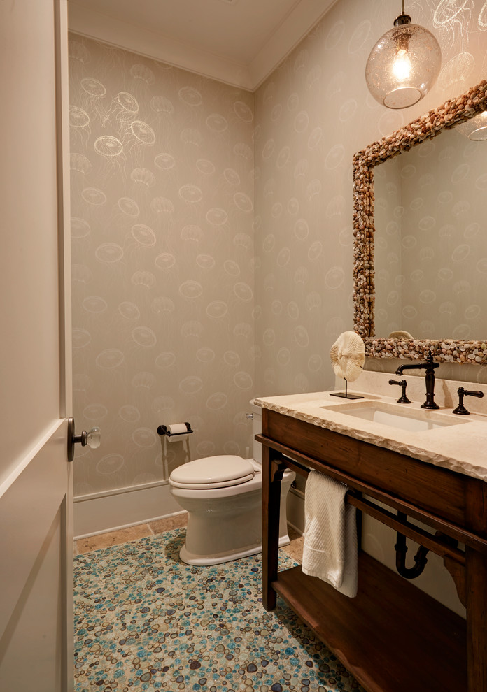 Inspiration for a small beach style powder room in Jacksonville with brown cabinets, a two-piece toilet, white tile, porcelain tile, beige walls, porcelain floors, an undermount sink, limestone benchtops and multi-coloured floor.