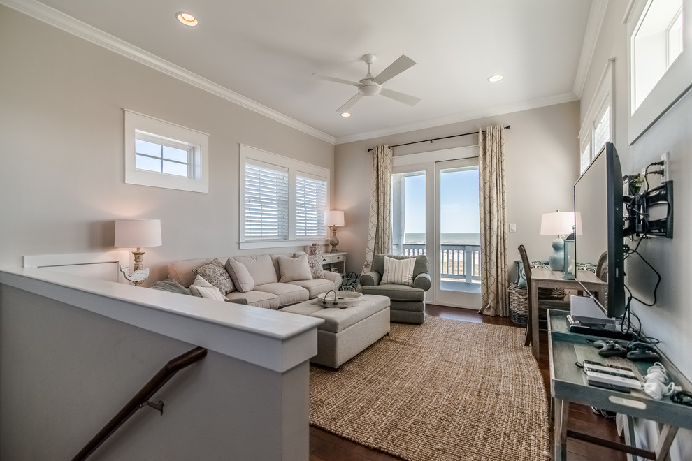 This is an example of a small beach style open concept family room in Houston with a game room, grey walls, medium hardwood floors, a wall-mounted tv and brown floor.