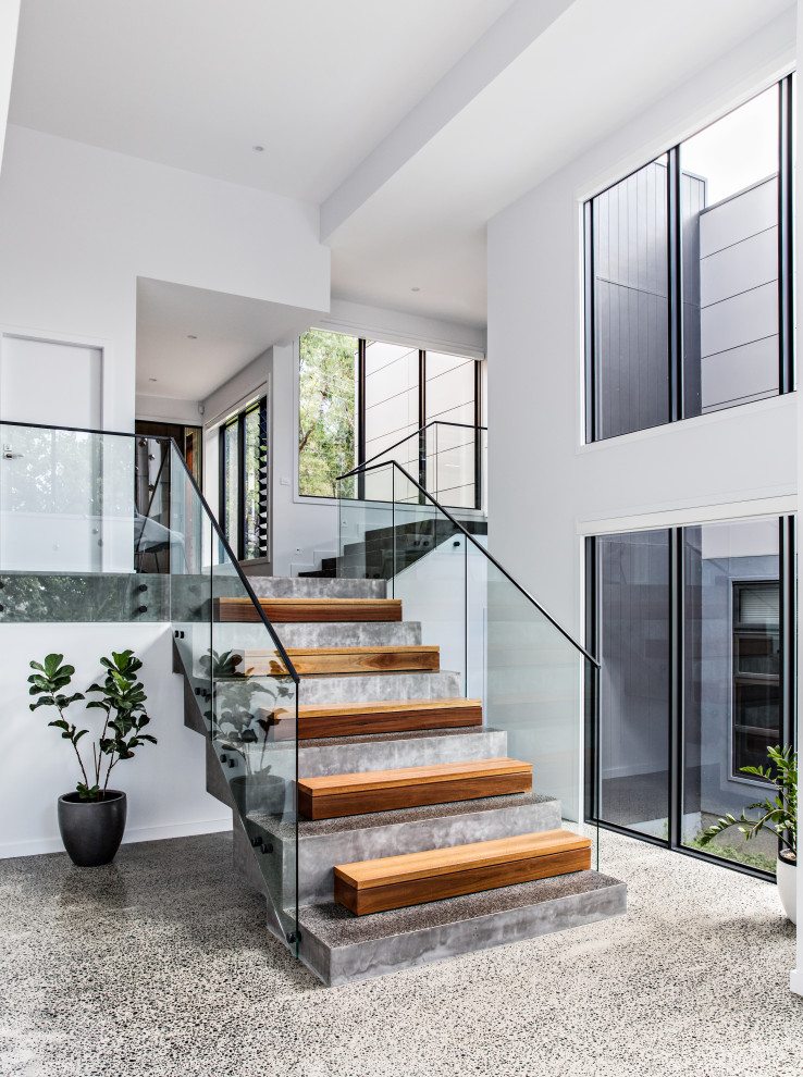 This is an example of a small contemporary concrete l-shaped staircase in Wollongong with concrete risers and glass railing.