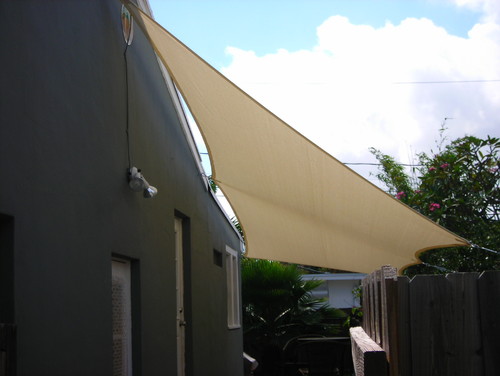 Tan sun shade covering space between a building and fence by Smart Shade Solutions