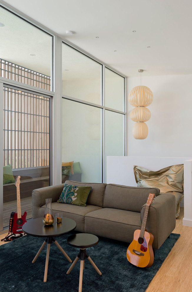 Photo of a mid-sized contemporary open concept family room in Austin with white walls, a music area, light hardwood floors, no fireplace, no tv and brown floor.
