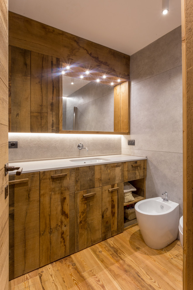 Inspiration for a country 3/4 bathroom in Other with medium wood cabinets, medium hardwood floors, flat-panel cabinets, a bidet, gray tile, an undermount sink, brown floor and white benchtops.