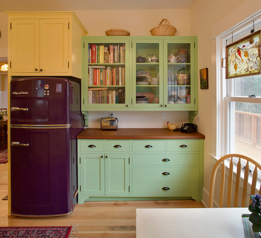 Inspiration for a traditional kitchen in Portland with glass-front cabinets, green cabinets, wood benchtops and coloured appliances.