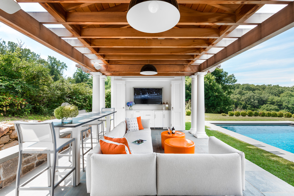 This is an example of a beach style backyard patio in New York with a pergola.