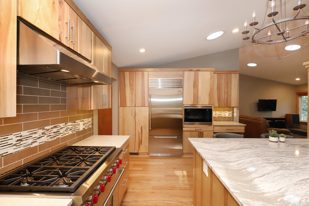Eat-in kitchen - mid-sized transitional u-shaped light wood floor and brown floor eat-in kitchen idea in Grand Rapids with an undermount sink, flat-panel cabinets, light wood cabinets, quartz countertops, brown backsplash, ceramic backsplash, stainless steel appliances and an island