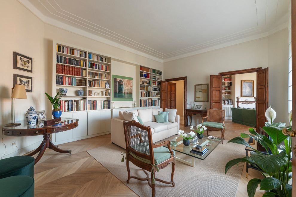 Ispirazione per un ampio soggiorno chic con libreria, pareti beige e parquet chiaro