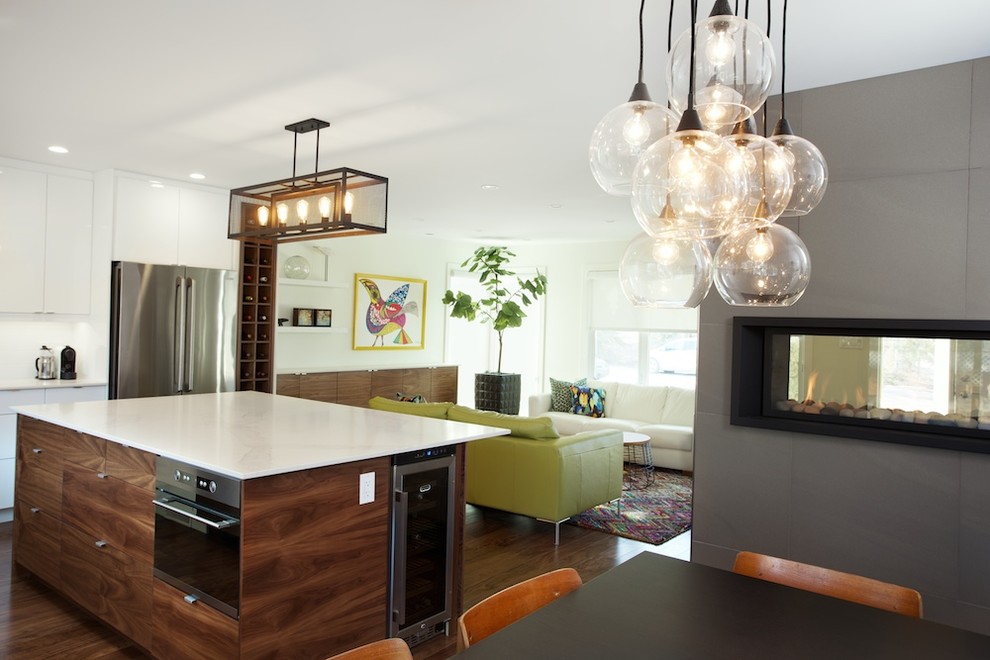 This is an example of a small contemporary open plan dining in Edmonton with white walls, medium hardwood floors, a two-sided fireplace and a tile fireplace surround.