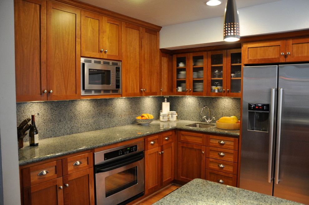 Eat-in kitchen - mid-sized transitional l-shaped medium tone wood floor and brown floor eat-in kitchen idea with a farmhouse sink, medium tone wood cabinets, granite countertops, stone slab backsplash, stainless steel appliances, a peninsula, green backsplash and shaker cabinets