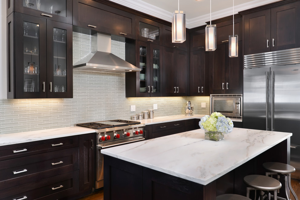 Kitchen - large transitional l-shaped medium tone wood floor kitchen idea in Chicago with shaker cabinets, dark wood cabinets, gray backsplash, glass tile backsplash, stainless steel appliances, an undermount sink, marble countertops and an island