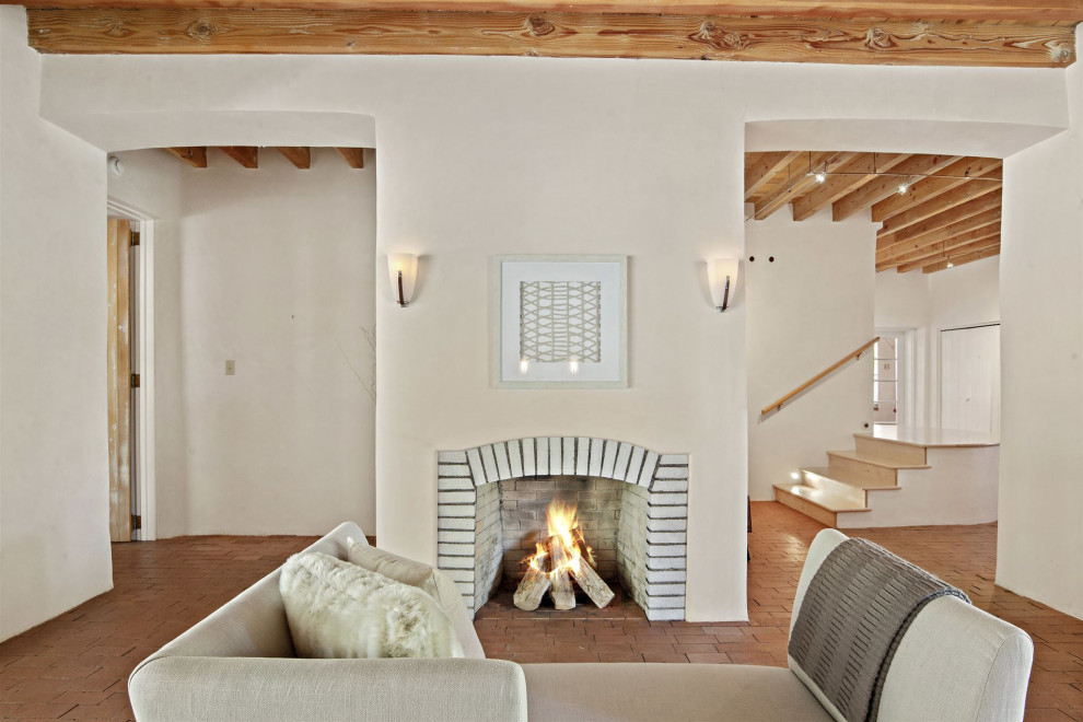 Inspiration for an expansive open concept living room in Other with beige walls, brick floors, a standard fireplace, a brick fireplace surround, no tv, orange floor and exposed beam.
