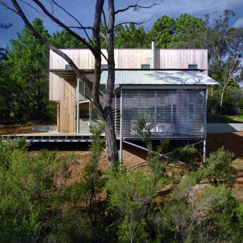 Photo of a mid-sized contemporary two-storey grey house exterior in Sydney with wood siding, a shed roof and a metal roof.