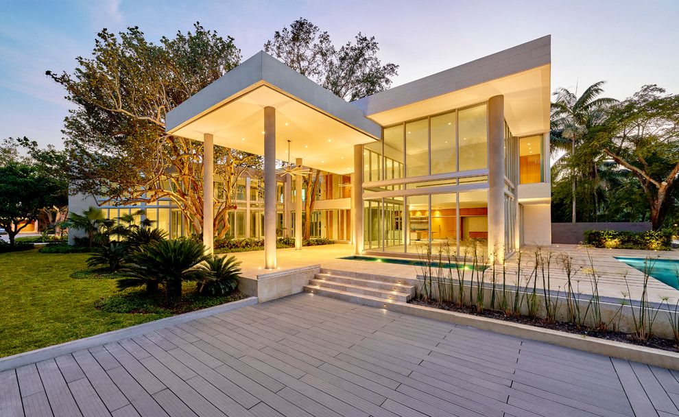 Photo of a large modern two-storey grey exterior in Miami with stone veneer and a flat roof.