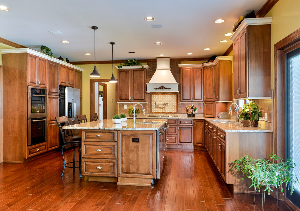 Eat-in kitchen - large transitional u-shaped medium tone wood floor eat-in kitchen idea with beaded inset cabinets, medium tone wood cabinets, granite countertops, beige backsplash, mosaic tile backsplash, stainless steel appliances and an island