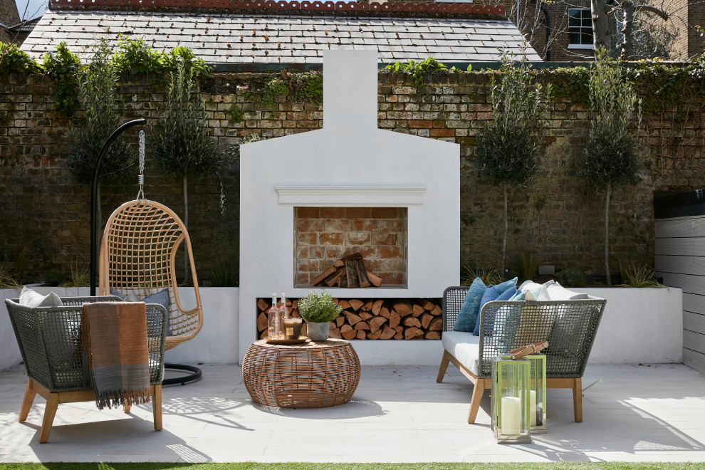 Inspiration for a contemporary back patio in London with a fireplace, concrete slabs and no cover.