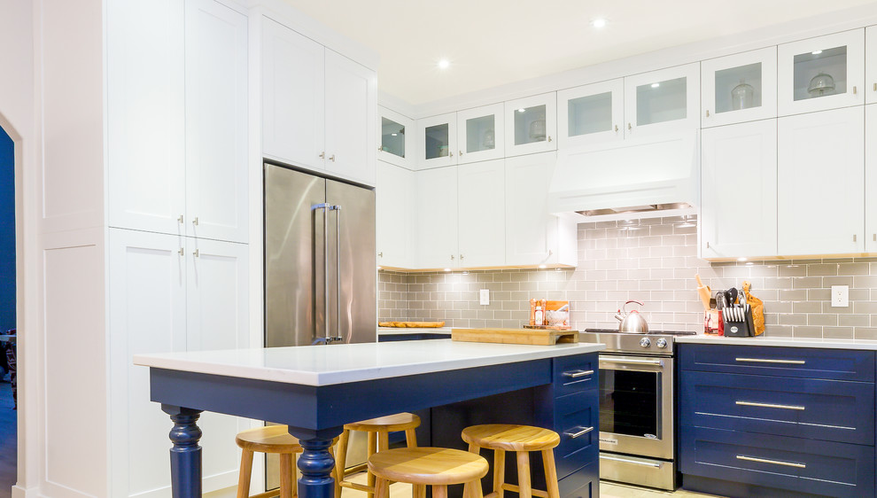 Open concept kitchen - large transitional u-shaped light wood floor open concept kitchen idea with a farmhouse sink, shaker cabinets, blue cabinets, quartz countertops, gray backsplash, glass tile backsplash, stainless steel appliances, an island and white countertops