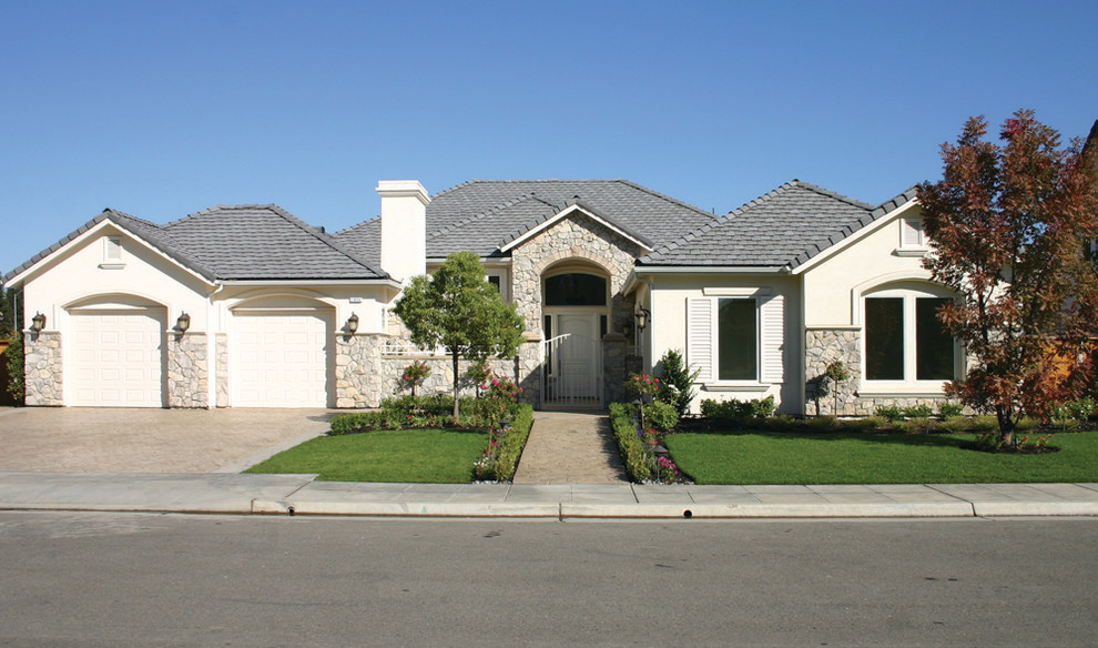 This is an example of a large transitional one-storey white house exterior in San Francisco with stone veneer and a gable roof.
