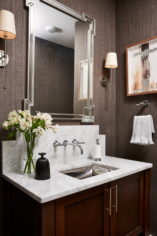 Photo of a mid-sized modern powder room in Minneapolis with recessed-panel cabinets, dark wood cabinets, grey walls, an undermount sink, marble benchtops, white benchtops, a built-in vanity and wallpaper.