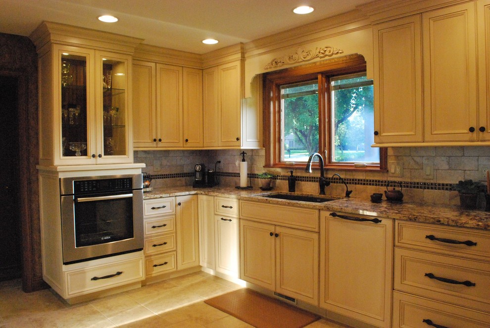 Eat-in kitchen - mid-sized u-shaped eat-in kitchen idea with beaded inset cabinets, beige cabinets, granite countertops, brown backsplash, stone tile backsplash, stainless steel appliances and no island