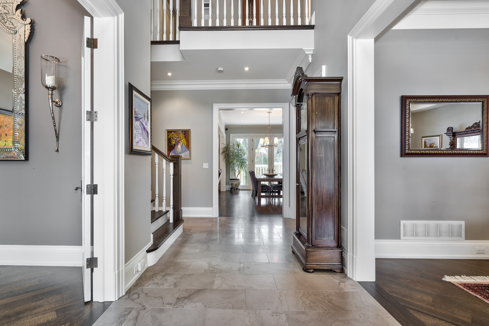 Large transitional porcelain tile and beige floor foyer photo in Toronto with gray walls and a dark wood front door