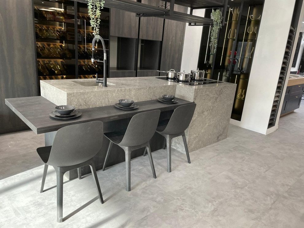 Inspiration for a medium sized industrial grey and brown single-wall kitchen in Kent with an integrated sink, flat-panel cabinets, dark wood cabinets, quartz worktops, black appliances, vinyl flooring, an island, grey floors, grey worktops and feature lighting.