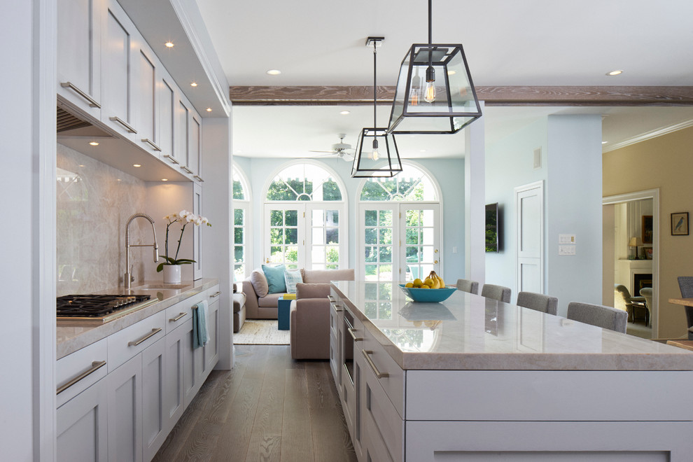 This is an example of a large transitional l-shaped eat-in kitchen in New York with shaker cabinets, with island, an undermount sink, white cabinets, quartzite benchtops, grey splashback, stone slab splashback, stainless steel appliances and dark hardwood floors.