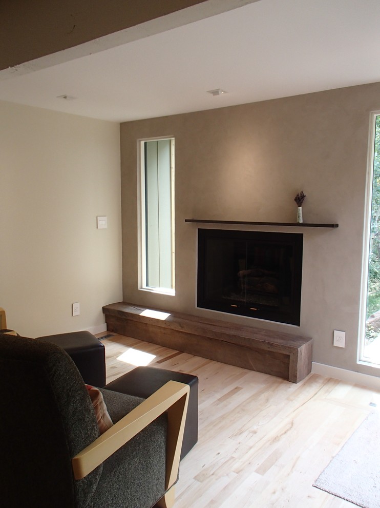 Small transitional enclosed living room in Denver with beige walls, light hardwood floors, a standard fireplace, a plaster fireplace surround and beige floor.