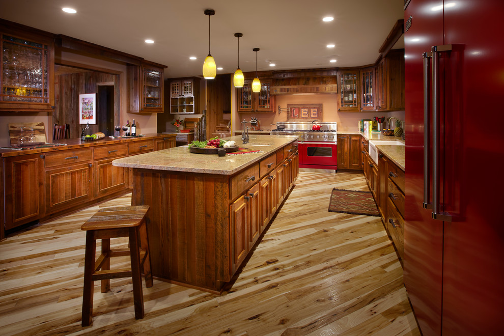 This is an example of an expansive country u-shaped eat-in kitchen in Milwaukee with a farmhouse sink, recessed-panel cabinets, medium wood cabinets, granite benchtops, beige splashback, coloured appliances, light hardwood floors and with island.