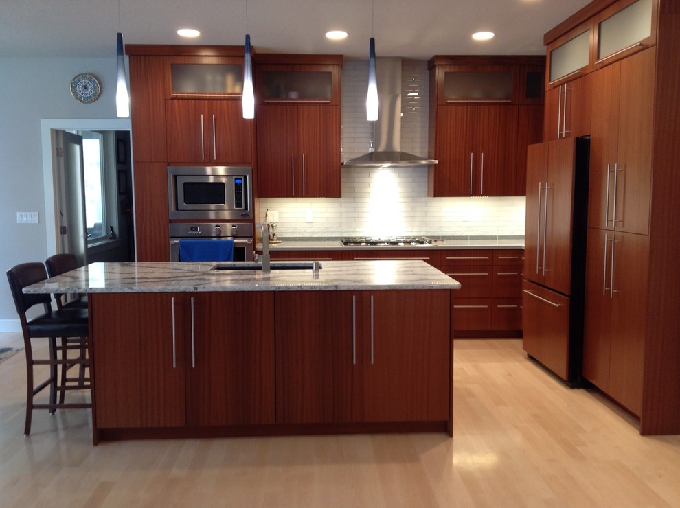Inspiration for a large transitional l-shaped light wood floor eat-in kitchen remodel in Seattle with a single-bowl sink, flat-panel cabinets, medium tone wood cabinets, quartz countertops, white backsplash, glass tile backsplash, stainless steel appliances and an island