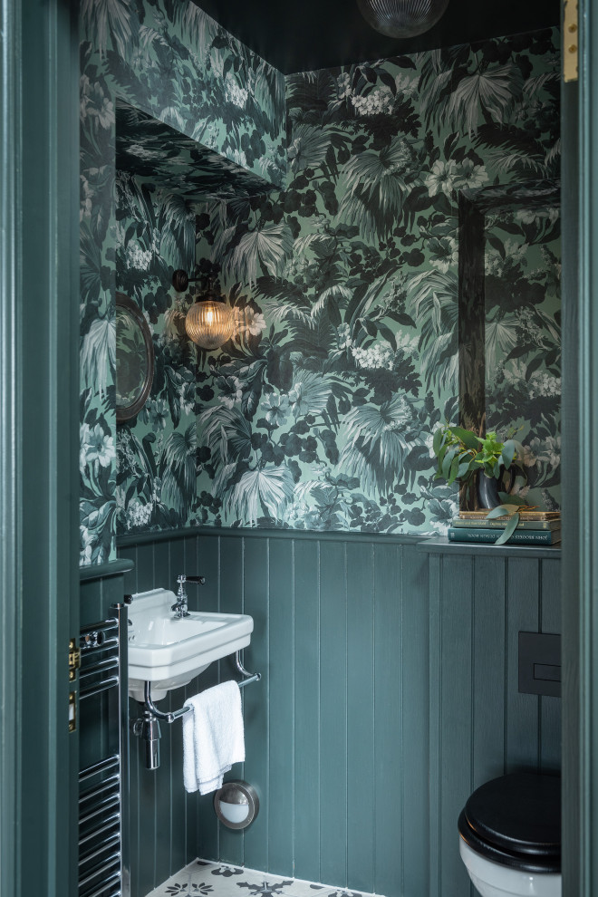 デヴォンにある小さなカントリー風のおしゃれなトイレ・洗面所 (壁掛け式トイレ、磁器タイルの床、壁付け型シンク、マルチカラーの床、壁紙) の写真