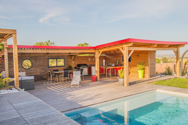 Réalisation d'un grand jardin avec une terrasse en bois ou composite arrière design l'été avec un mur de soutènement et une exposition ensoleillée.