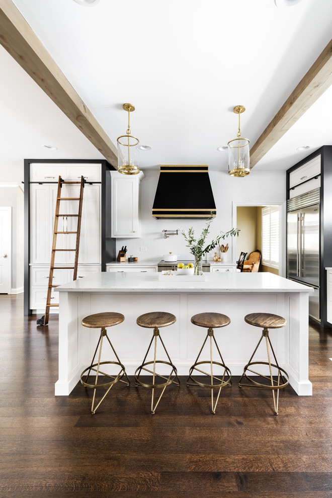 Inspiration for a mid-sized transitional l-shaped dark wood floor and brown floor open concept kitchen remodel in Chicago with a farmhouse sink, beaded inset cabinets, white cabinets, quartz countertops, white backsplash, ceramic backsplash, stainless steel appliances and an island