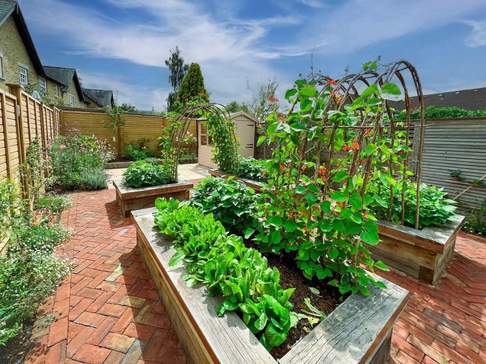 Design ideas for a mid-sized traditional backyard full sun formal garden for summer in Surrey with a vegetable garden, brick pavers and a wood fence.