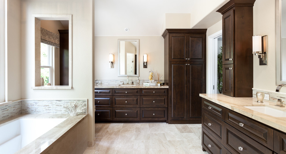 Photo of a large traditional master bathroom in Sacramento with dark wood cabinets, an undermount tub, beige tile, stone tile, beige walls, marble floors, an undermount sink, marble benchtops and raised-panel cabinets.