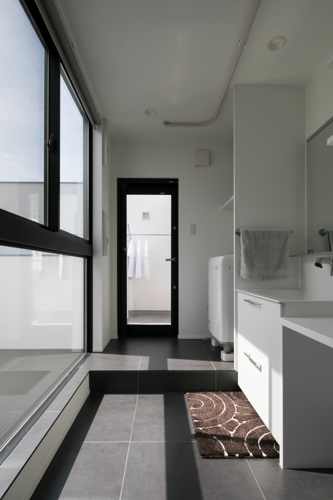 This is an example of a mid-sized asian single-wall dedicated laundry room in Tokyo with an undermount sink, beaded inset cabinets, white cabinets, white walls, porcelain floors, grey floor and white benchtop.