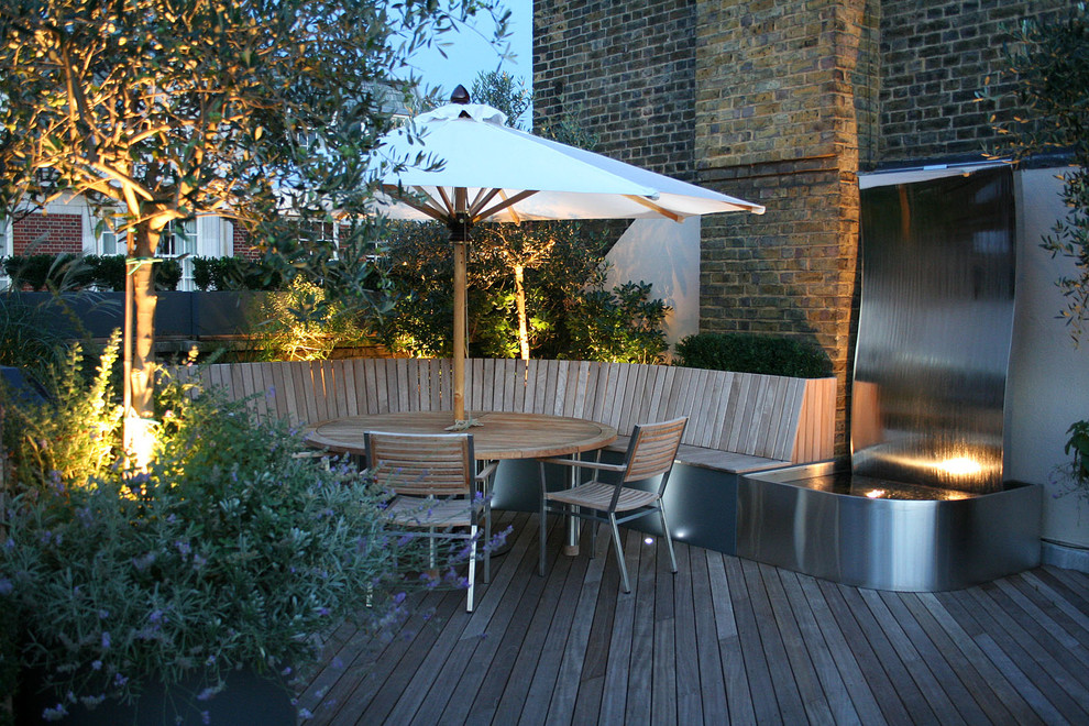 Photo of a contemporary backyard deck in London with no cover and a water feature.