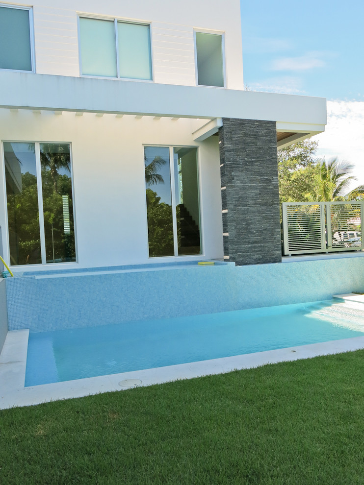 Design ideas for a small contemporary front yard patio in Miami with a water feature and natural stone pavers.