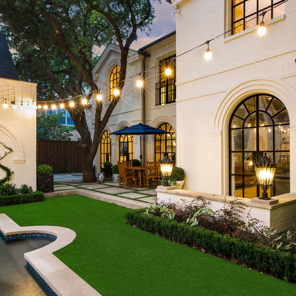 This is an example of a transitional full sun garden in Dallas with a water feature.