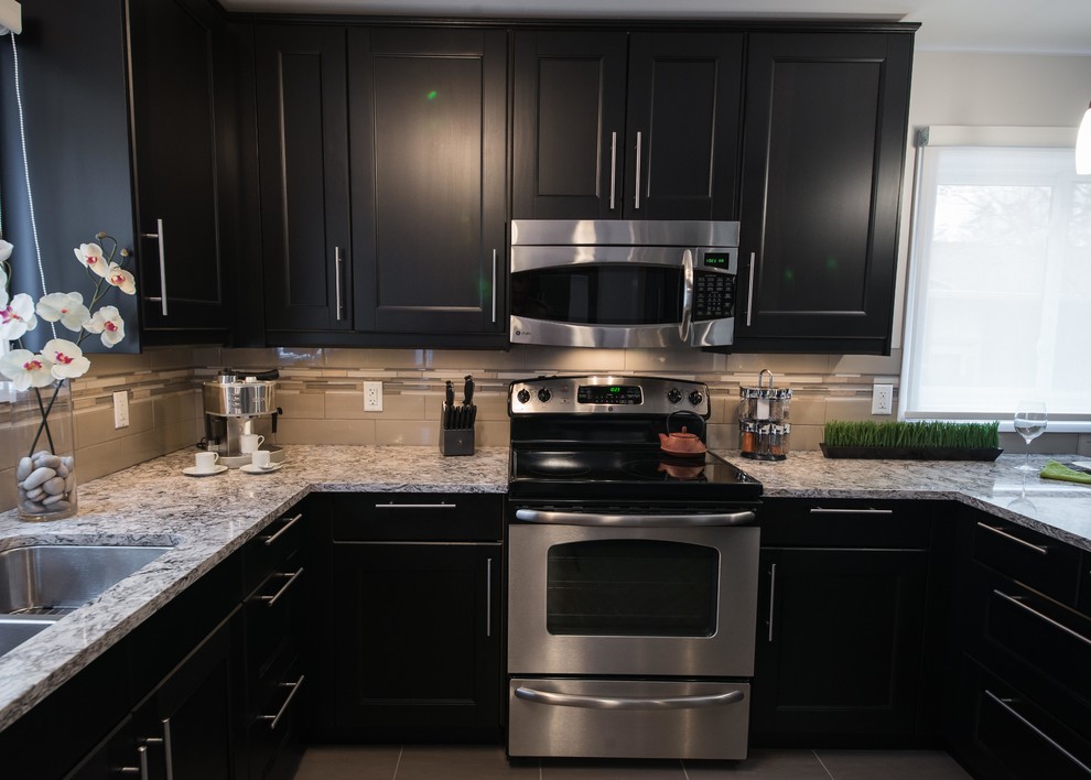 Inspiration for a transitional u-shaped eat-in kitchen in Ottawa with an undermount sink, shaker cabinets, black cabinets, quartz benchtops, grey splashback, porcelain splashback and stainless steel appliances.