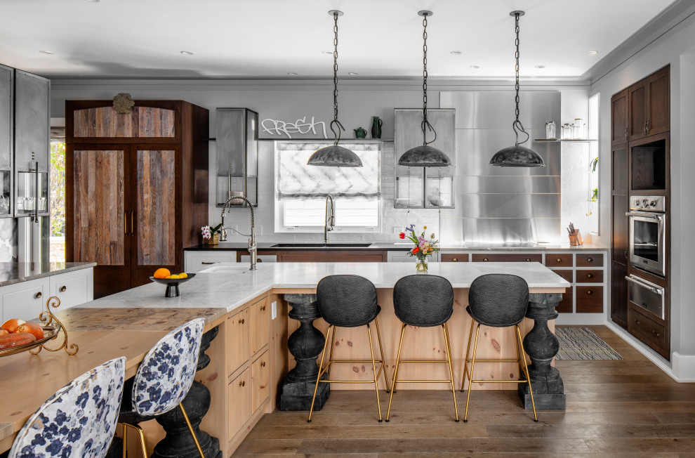 Beach style eat-in kitchen in Chicago with a double-bowl sink, distressed cabinets, white splashback, stainless steel appliances, medium hardwood floors, multiple islands and white benchtop.