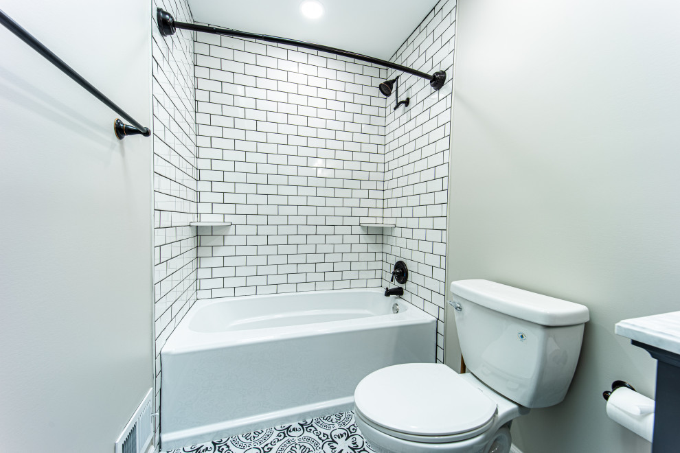 Пример оригинального дизайна: ванная комната среднего размера в стиле неоклассика (современная классика) с фасадами в стиле шейкер, черными фасадами, ванной в нише, душем в нише, раздельным унитазом, белой плиткой, керамической плиткой, серыми стенами, полом из керамической плитки, монолитной раковиной, мраморной столешницей, черным полом, шторкой для ванной, белой столешницей, тумбой под одну раковину и напольной тумбой