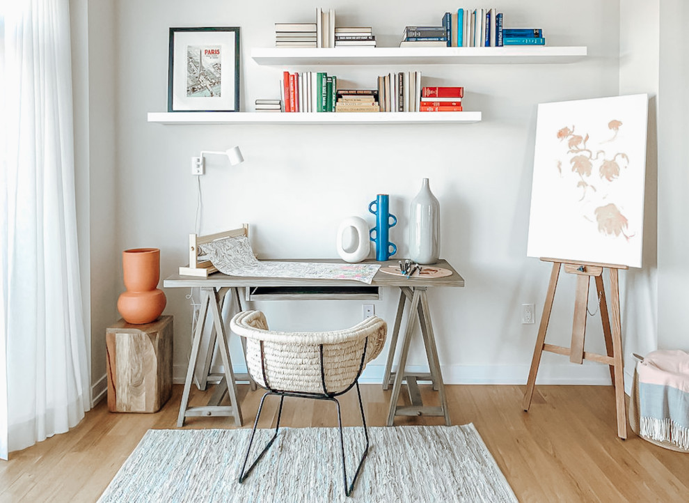 Immagine di un piccolo atelier con pareti bianche, parquet chiaro, scrivania autoportante e pavimento marrone