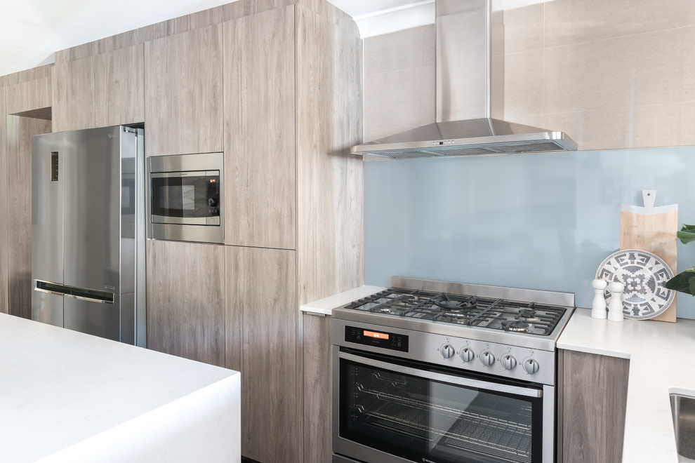 Inspiration for a contemporary kitchen in Perth with a double-bowl sink, quartz benchtops, blue splashback, glass sheet splashback, stainless steel appliances, with island and brown floor.