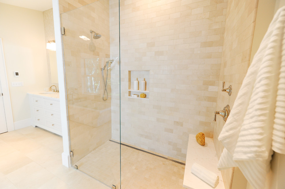 This is an example of a beach style master bathroom in Boston with recessed-panel cabinets, white cabinets, a freestanding tub, an alcove shower, a two-piece toilet, beige tile, travertine, beige walls, porcelain floors, an undermount sink, marble benchtops, beige floor and an open shower.