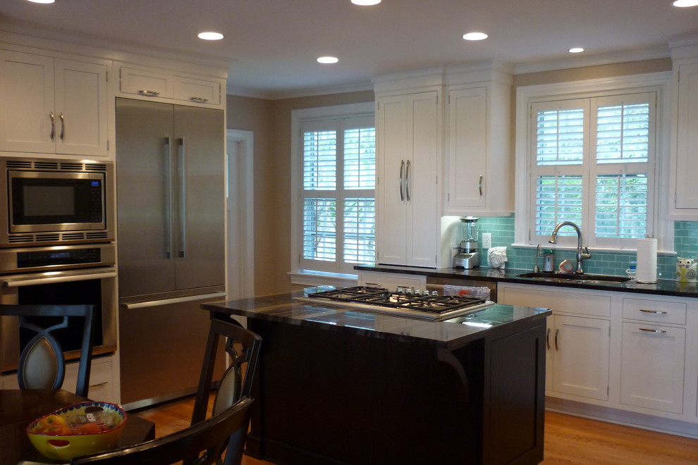 Photo of a small beach style l-shaped eat-in kitchen in Charleston with an undermount sink, beaded inset cabinets, white cabinets, granite benchtops, blue splashback, glass tile splashback, stainless steel appliances, with island and medium hardwood floors.