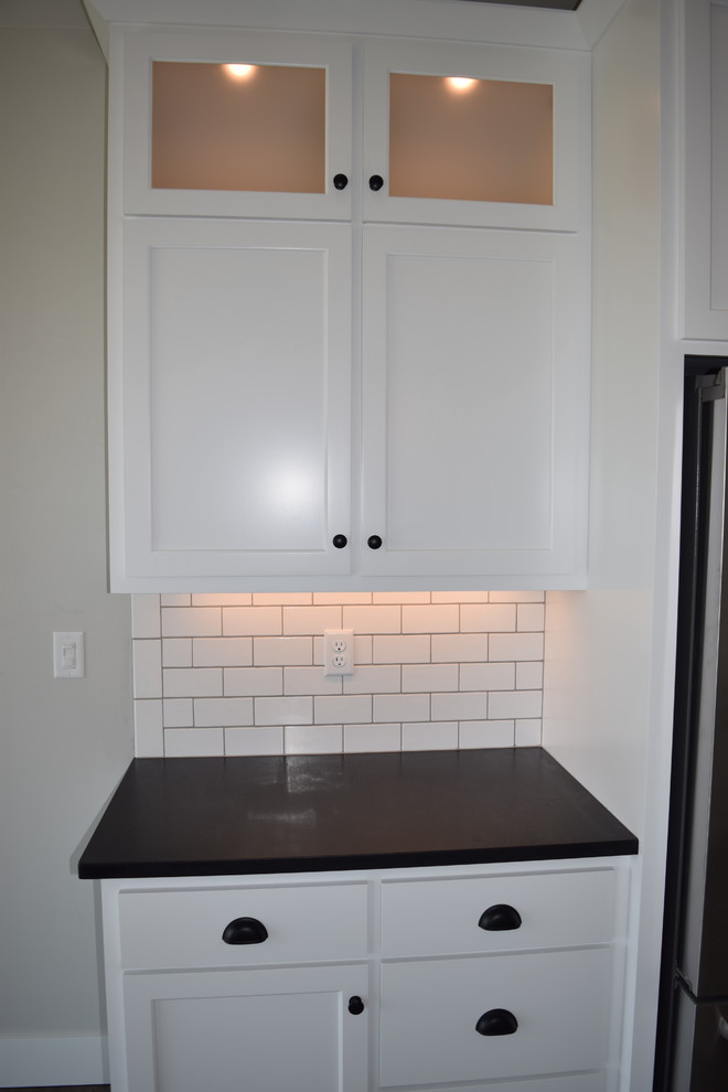 Open concept kitchen - large l-shaped dark wood floor and brown floor open concept kitchen idea with an undermount sink, recessed-panel cabinets, white cabinets, granite countertops, white backsplash, ceramic backsplash, stainless steel appliances and an island