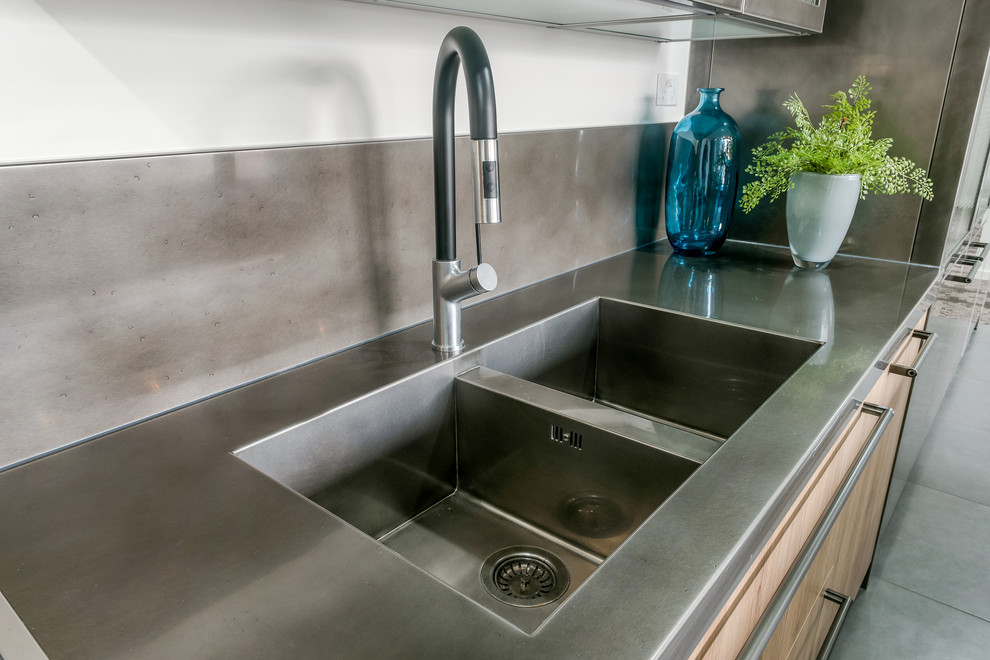 This is an example of an industrial galley eat-in kitchen in Melbourne with an integrated sink, raised-panel cabinets, medium wood cabinets, stainless steel benchtops, metallic splashback, stainless steel appliances, ceramic floors and multiple islands.