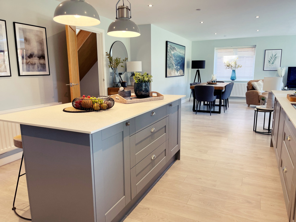 Large eclectic l-shaped open plan kitchen in Hampshire with shaker cabinets, grey cabinets, marble benchtops, ceramic floors, with island, brown floor and white benchtop.