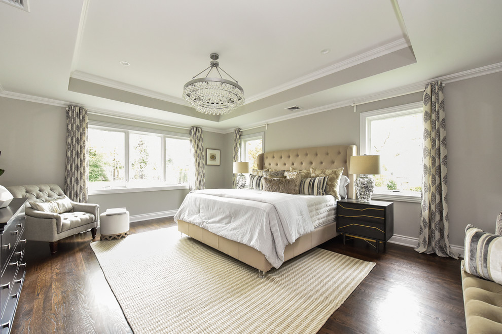 This is an example of an expansive transitional master bedroom in New York with grey walls, dark hardwood floors, brown floor and no fireplace.